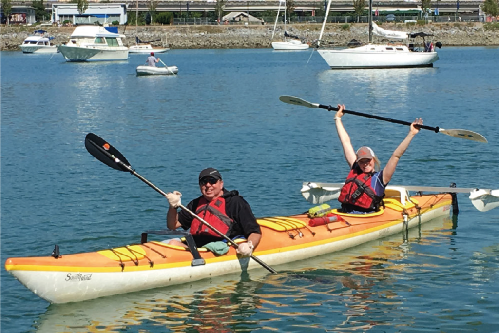 People posing in two person kayak.