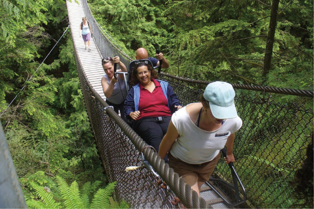 Hikers walking across the Capilano Suspension Bridge with a TrailRider.